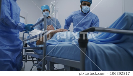 Multi ethnic surgeons push stretcher with patient 106892817
