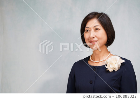 Smiling middle-aged woman wearing a pearl necklace and corsage Smiling middle-aged woman wearing a pearl necklace and corsage 106895322