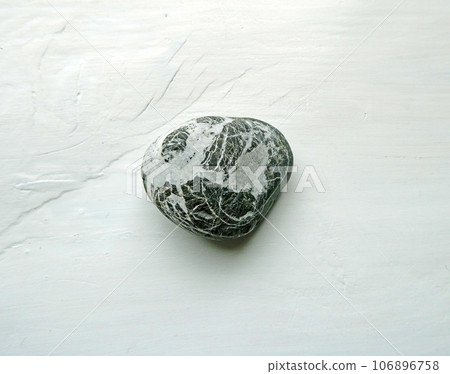 A photo of seaside pebbles with unique shapes and patterns laid out on a white background A photo of seaside pebbles with unique shapes and patterns laid out on a white background 106896758