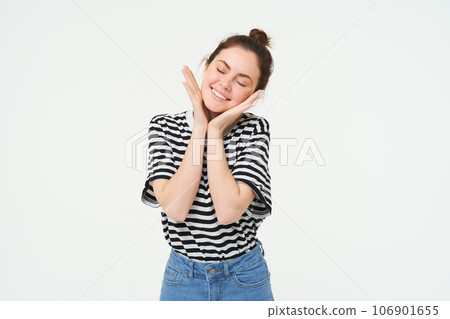 Image of happy young woman, laughing and smiling, looking pleased, touches her clear glowing skin, standing over white background Image of happy young woman, laughing and smiling, looking pleased, touches her clear glowing skin, standing over white background 106901655