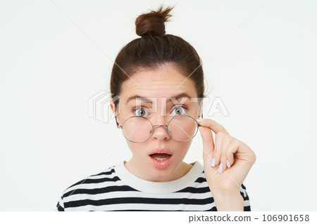 Image of woman in glasses, looks surprised, takes off eyewear, looks amazed, says wow, impressed by something, stands over white background Image of woman in glasses, looks surprised, takes off eyewear, looks amazed, says wow, impressed by something, stands over white background 106901658