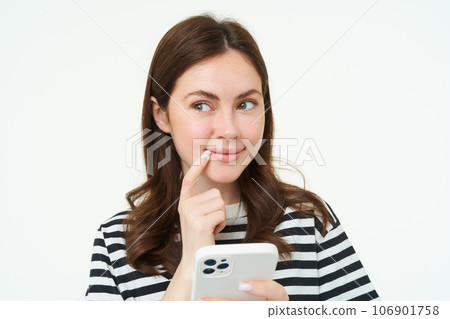 Portrait of smiling woman thinks to order something online on smartphone app, holding mobile phone with thoughtful face Portrait of smiling woman thinks to order something online on smartphone app, holding mobile phone with thoughtful face 106901758