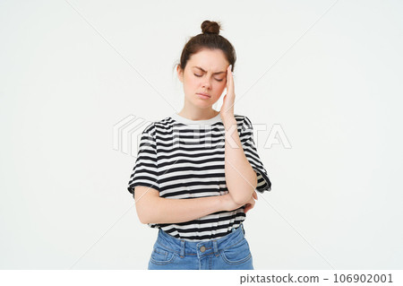 Portrait of tired woman rubs her forehead, touches head, has a headache, stands distressed against white background 106902001