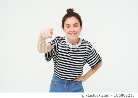 Image of stylish young woman, pointing finger at camera, inviting you, standing over white background Image of stylish young woman, pointing finger at camera, inviting you, standing over white background 106902233