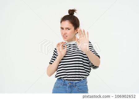 Disgusted woman steps back, raising hands defensive, avoiding something, rejecting and refusing offer, standing over white background Disgusted woman steps back, raising hands defensive, avoiding something, rejecting and refusing offer, standing over white background 106902652