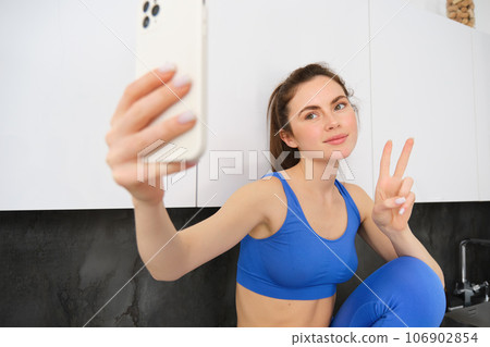 Fit and healthy young sports woman, showing peace sign, taking selfie in activewear, fitness blogger making photos for social media in her activewear 106902854