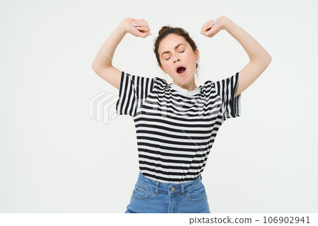 Portrait of tired girl yawning and stretching her arms. Lazy woman looking sleepy, standing over white background 106902941