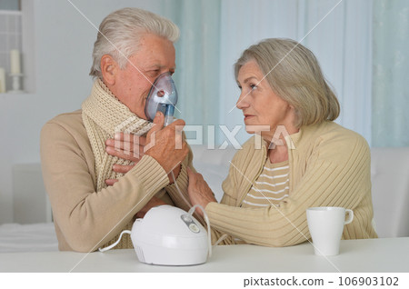 Portrait of sick senior woman with inhaler and man at home 106903102