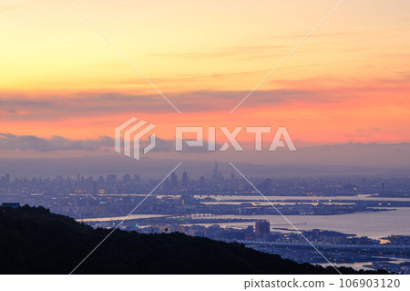 黎明前,天空和海灣被染成橙色。從神戶市上方的山上俯瞰大阪灣和大阪南港。 黎明前,天空和海灣被染成橙色。從神戶市上方的山上俯瞰大阪灣和大阪南港。 106903120