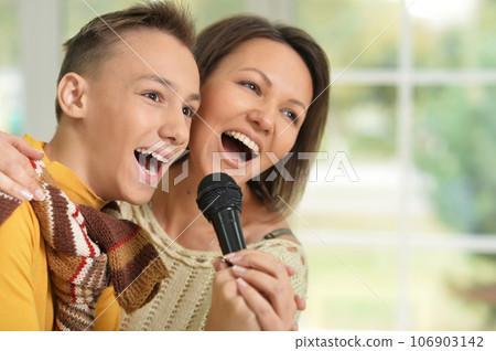 mother and his son singing into the microphone. 106903142