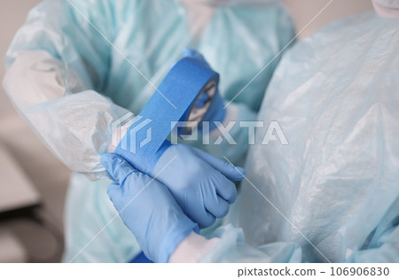 Nurse gluing tape on sleeve of surgical suit closeup Nurse gluing tape on sleeve of surgical suit closeup 106906830