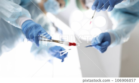 Group of doctors are holding surgical instruments over patient closeup 106906857