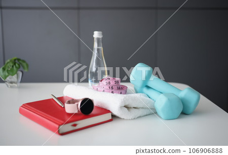 Dumbbells, smart watches and diary with water are on table Dumbbells, smart watches and diary with water are on table 106906888