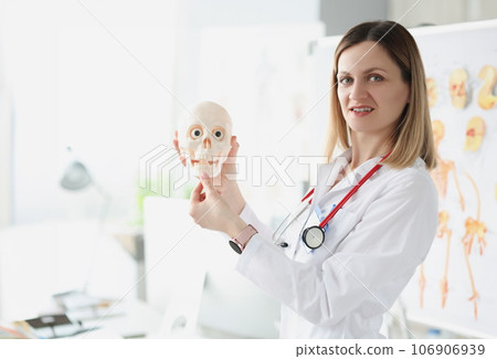 Female doctor teacher holding human skull closeup 106906939