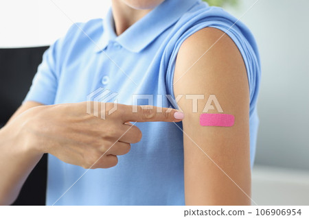 Pink plaster on woman shoulder after shot of vaccine 106906954