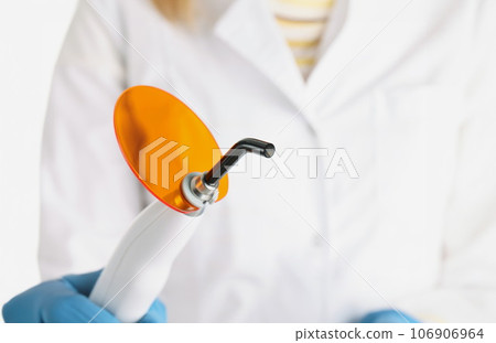 Doctor holds dental equipment that allows light to pass through 106906964
