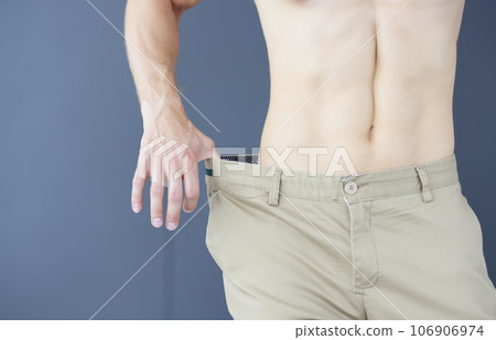 Slimming muscular man in pants that too big closeup 106906974