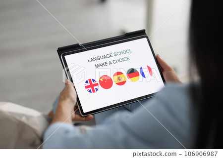 Woman holds tablet and chooses a foreign language to study Woman holds tablet and chooses a foreign language to study 106906987
