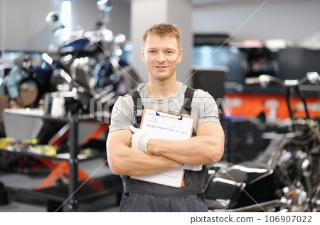 Handsome auto mechanic posing in car service and holding documents in hands 106907022