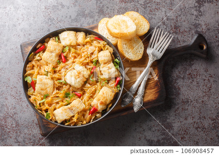 Delicious spicy stewed white cabbage with sea fish fillet, onion and chili pepper close-up in a plate on the table. horizontal top view 106908457
