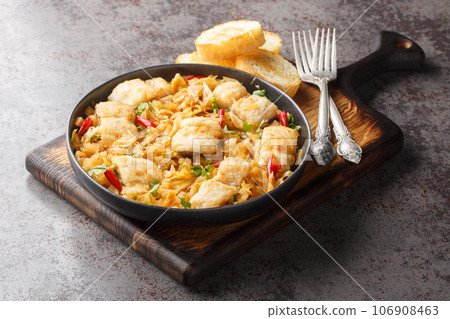 Spicy stew of white fish fillet with sauerkraut and onions close-up in a plate served with toast. Horizontal Spicy stew of white fish fillet with sauerkraut and onions close-up in a plate served with toast. Horizontal 106908463