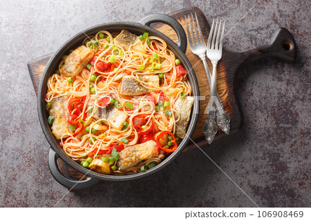 Main course spaghetti with white fish fillet, peppers, onions, green peas and tomato sauce close-up in a frying pan. Horizontal top view Main course spaghetti with white fish fillet, peppers, onions, green peas and tomato sauce close-up in a frying pan. Horizontal top view 106908469