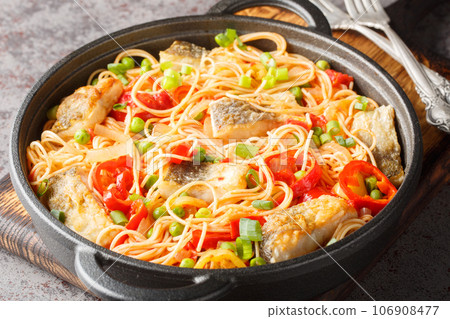 Delicious spaghetti with white fish fillet, pepper, onion, green peas and tomato sauce close-up in a frying pan. Horizontal Delicious spaghetti with white fish fillet, pepper, onion, green peas and tomato sauce close-up in a frying pan. Horizontal 106908477