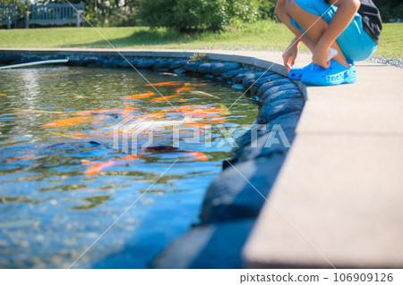 一個孩子看著錦鯉池 106909126