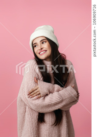 woman in hat, sweater hugging herself and smiling feeling happ 106909716