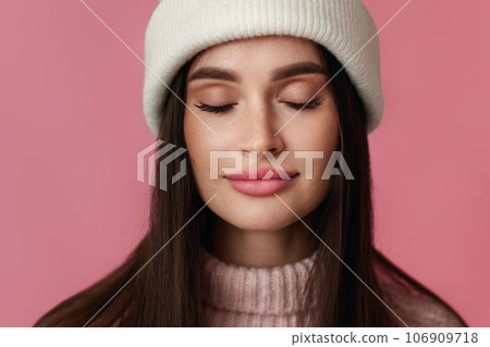 woman in white hat, pink sweater on pastel pink background. 106909718