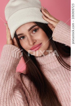 portrait of happy playful woman keeps hands on white knitted hat 106909723