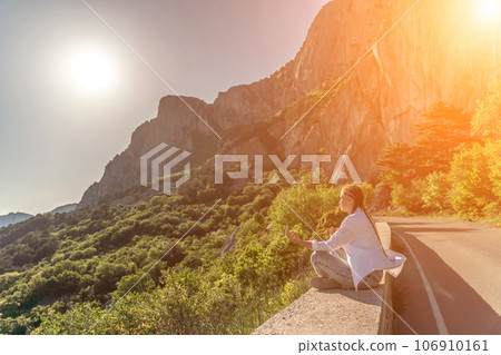 Yoga woman mountains. Profile of a woman doing yoga in the top of a cliff in the mountain. Woman meditates in yoga asana Padmasana Yoga woman mountains. Profile of a woman doing yoga in the top of a cliff in the mountain. Woman meditates in yoga asana Padmasana 106910161