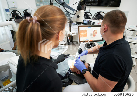 Dentist scanning patient's teeth with modern machine for intraoral scanning. Digital print of patient's teeth is on big screen. Modern high precision technologies. Concept of modern dentistry 106910626