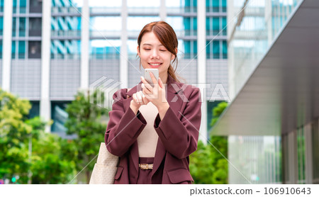 Smiling business woman operating a smartphone Smiling business woman operating a smartphone 106910643