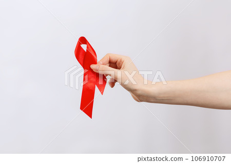 A female's hand holds a red ribbon. White background. Copy space. The concept of world AIDS day 106910707