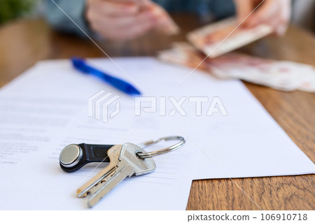 World leasing day. Realtor counts the money, in a blur. There are papers and keys on the table. Close up World leasing day. Realtor counts the money, in a blur. There are papers and keys on the table. Close up 106910718