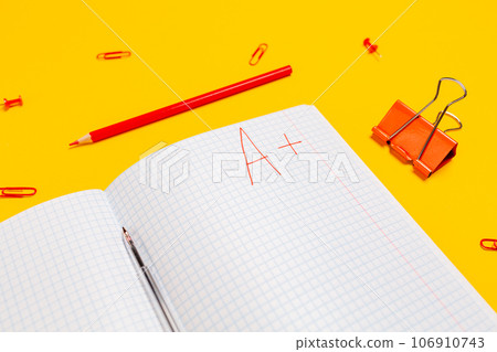 A composition of notebook with an excellent grade on a yellow background. Flat lay. Concept of back to school A composition of notebook with an excellent grade on a yellow background. Flat lay. Concept of back to school 106910743