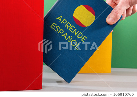 A male's hand holds an blue Spanish textbook. Close-up. Spanish Language Day Concept A male's hand holds an blue Spanish textbook. Close-up. Spanish Language Day Concept 106910760