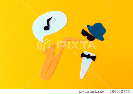 Silhouette of a musician with a saxophone from which melodie flew out, on a yellow background, cutted out of felt. Flat lay. Jazz Day Silhouette of a musician with a saxophone from which melodie flew out, on a yellow background, cutted out of felt. Flat lay. Jazz Day 106910765