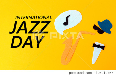 Silhouette of a musician with a saxophone from which melodie flew out, on a yellow background, cutted out of felt. Flat lay. International Jazz Day 106910767