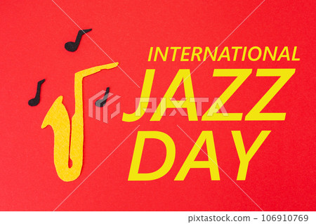 International Jazz Day. Silhouette of a saxophone from which melodies flew out, on a red background, cutted out of felt. Flat lay 106910769