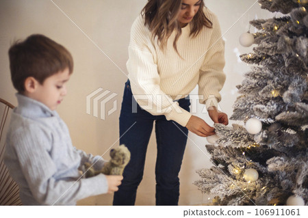 Family decorate xmas tree , mother with little son hanging tree toy balls on Christmas firtree 106911061