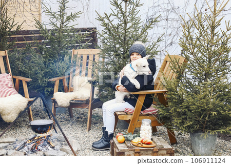 Smiling teenage girl in warm clothes holding cute white puppy in arms 106911124