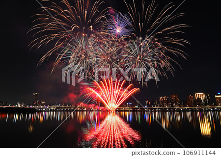 Colorful fireworks of various colors over night sky with    reflection in water   106911144