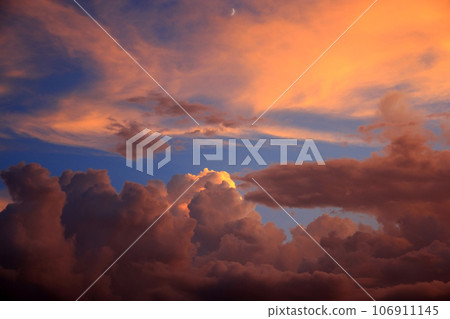 Cumulonimbus clouds and crescent moon rising in the sunset sky 106911145