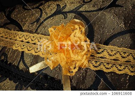 A beautiful yellow-orange lace artificial flower sewn onto a decorative cushion satin fabric. Blue dense braid with thin polyester lace. Decoration of decorative pillowcases. Women's needlework A beautiful yellow-orange lace artificial flower sewn onto a decorative cushion satin fabric. Blue dense braid with thin polyester lace. Decoration of decorative pillowcases. Women's needlework 106911608