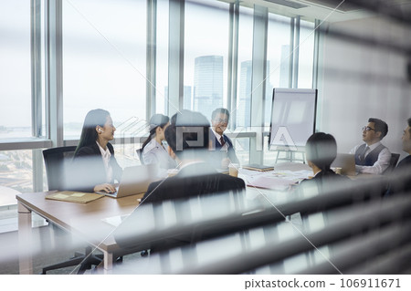 through-the-glass shot of a team of asian business people meeting in company conference room 106911671