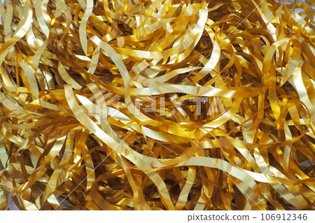 Tinsel-rain of golden color. New Year and Christmas decorations for the Christmas tree, interior or party room. Weaving threads of golden foil. Festive beautiful shiny background. Tinsel close-up 106912346