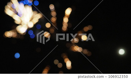 New Year's bokeh fireworks. Multicolored defocused sparks on the black night sky. Black background with abstract circles. A beautiful glowing explosion with yellow, blue and brown lights flying out New Year's bokeh fireworks. Multicolored defocused sparks on the black night sky. Black background with abstract circles. A beautiful glowing explosion with yellow, blue and brown lights flying out 106912350