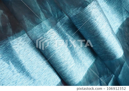 Satin curtains, blue striped tulle. Beautiful silky shiny fabric laid in waves. Room design in cool blue tones. Tailoring of curtains. Home interior design. Fabric sample Satin curtains, blue striped tulle. Beautiful silky shiny fabric laid in waves. Room design in cool blue tones. Tailoring of curtains. Home interior design. Fabric sample 106912352